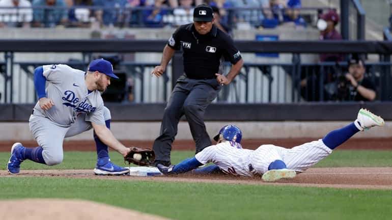 The Mets' Francisco Lindor steals third base ahead of a...