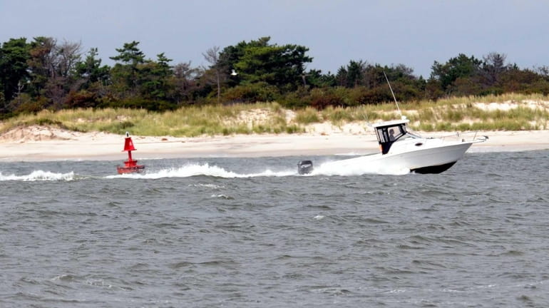 A boat navigates around a buoy in the Fire Island...