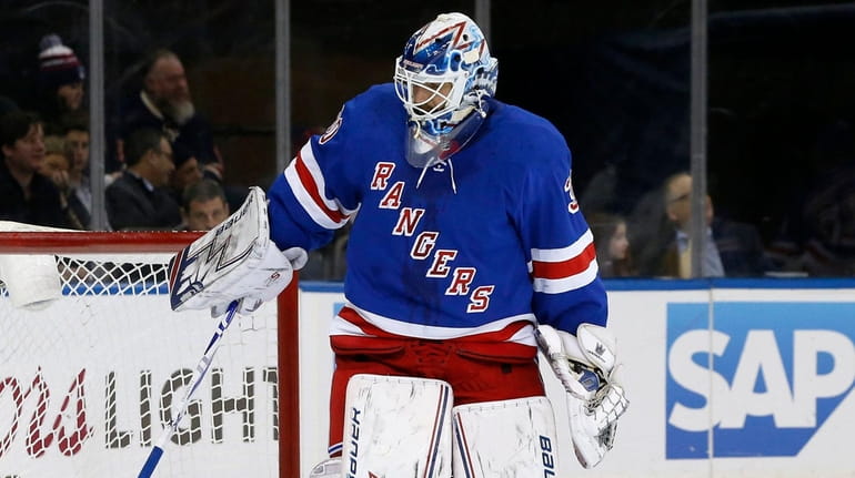 Henrik Lundqvist of theRangers digs the puck out of the net...
