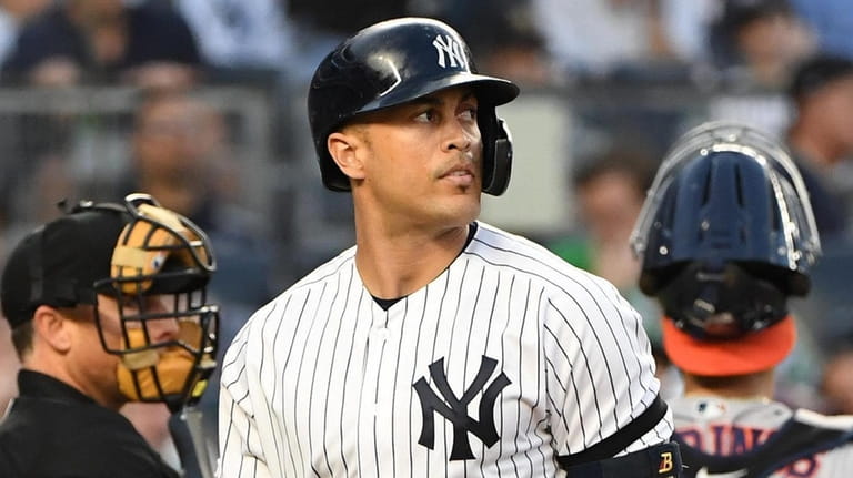 Yankees designated hitter Giancarlo Stanton reacts after he strikes out...