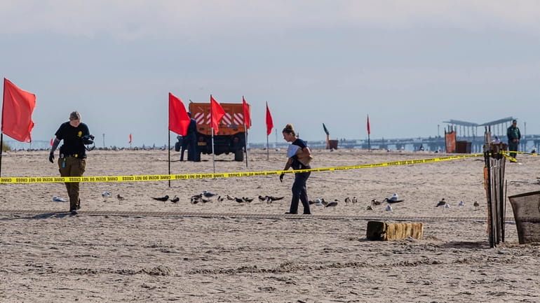 NYPD investigators gather evidence Monday on a Coney Island beach...