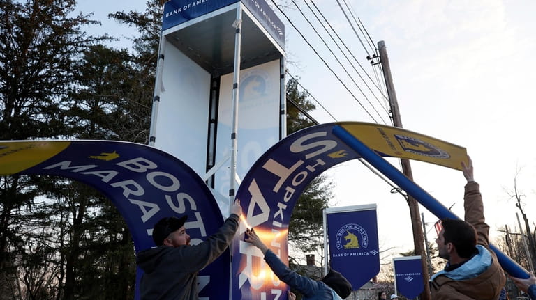 Workers affix banners at the starting line of the Boston...