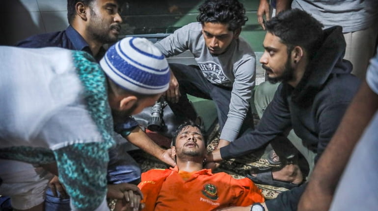 Locals help a Bangladeshi firefighter who lost consciousness while trying to...