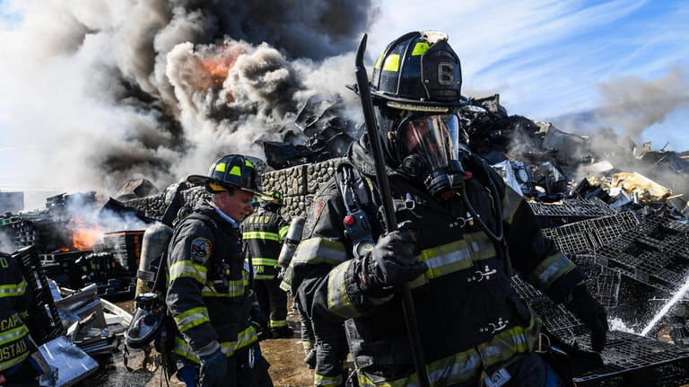 Volunteer firefighters from the West Babylon Fire Department extinguish a...