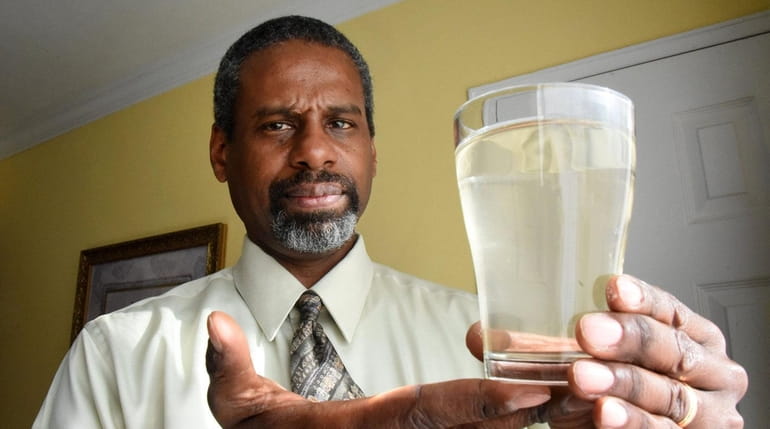 Lakeview resident Reginald Baron holds a glass of discolored water...