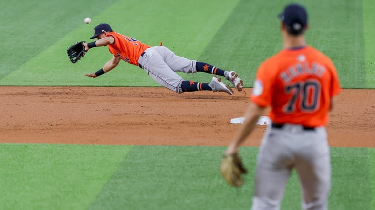 Houston Astros second baseman Mauricio Dubón, left, deflects a ground...