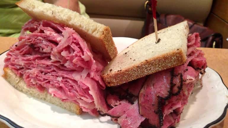 Half a corned beef sandwich on the left; half a...