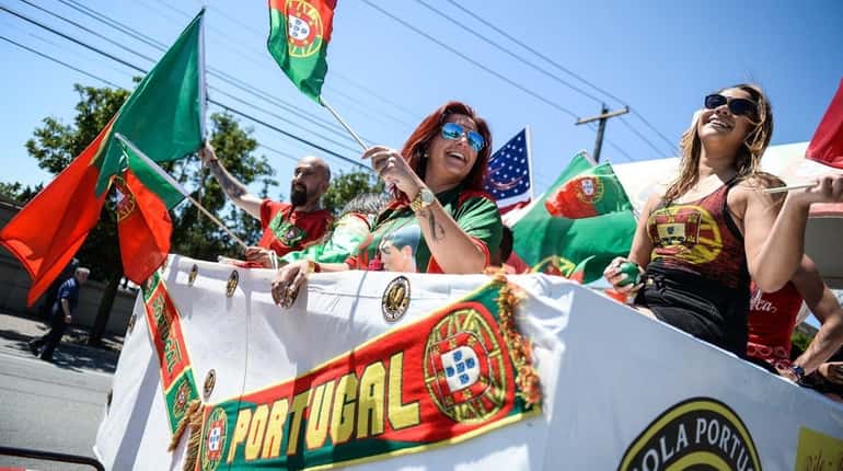 People on the Mineola Portuguese Center float wave to the...