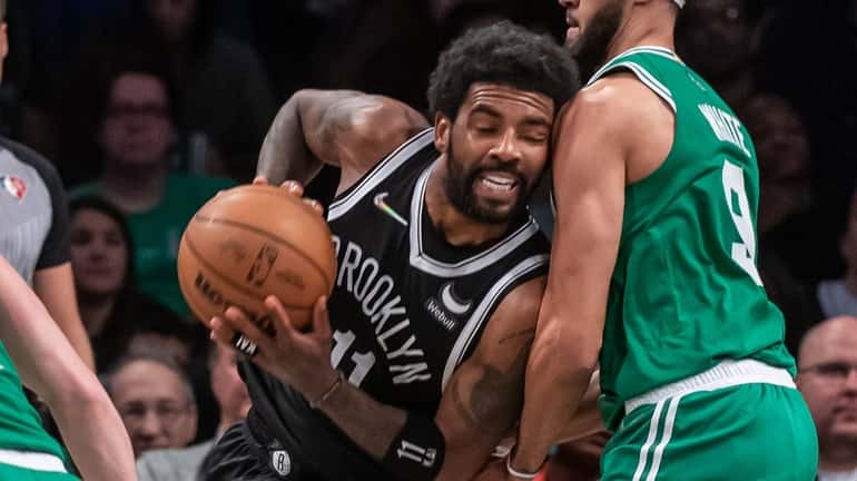 The Nets' Kyrie Irving tries to drive through Derrick White of...
