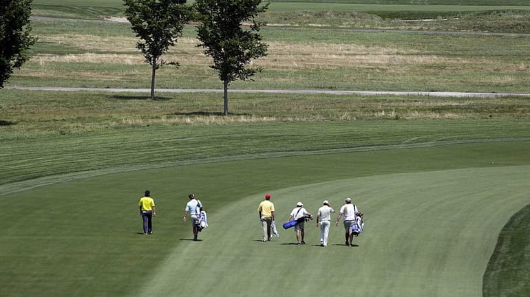 A group of golfers makes their way down the first...