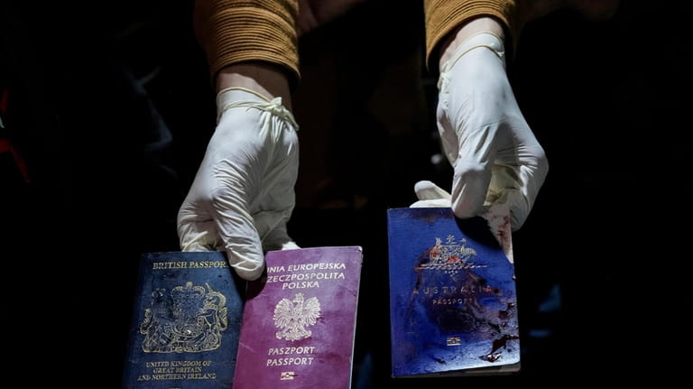 A man displays blood-stained British, Polish, and Australian passports after...