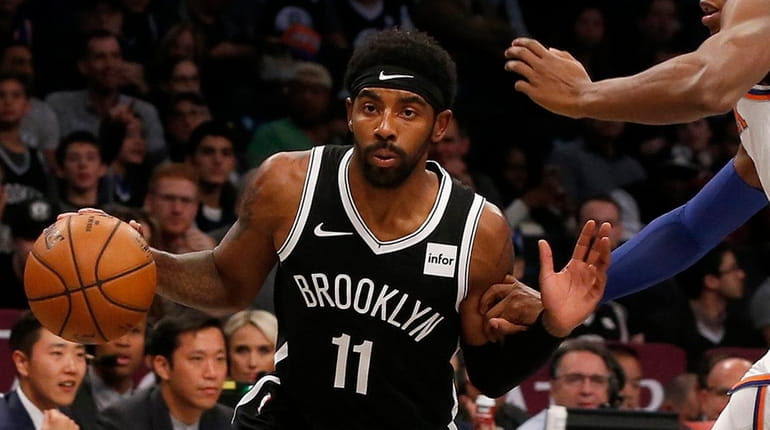 Kyrie Irving of the Nets drives against RJ Barrett of the Knicks...