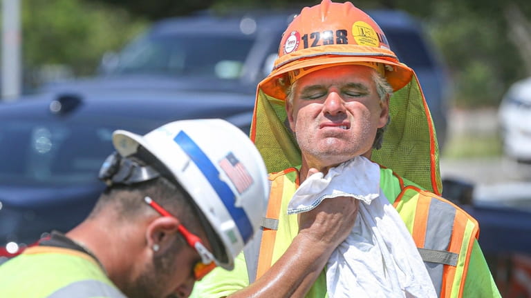 Construction worker James Hamill of Sagaponack wipes the sweat from his face...