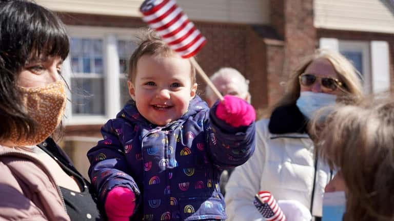 Thea Krolikowski, almost 2-years-old, waves an American flag at a...