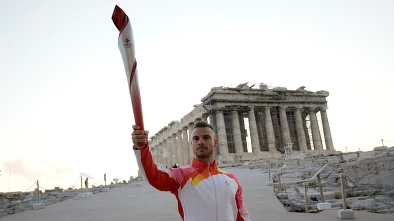 Greek torch bearer Christos Volikakis, world Champion in Cycling, holds...