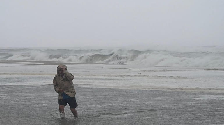 A man walks through the surf at Coopers Beach in...