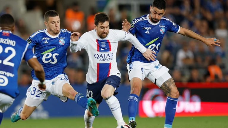 PSG's Lionel Messi, centre, challenges for the ball with Strasbourg's...