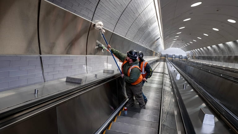 Workers buff and clean one of the deep escalators at...