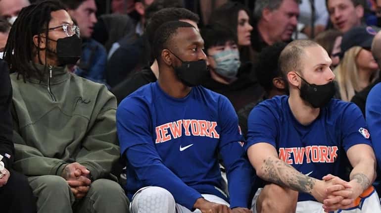 Knicks guard Kemba Walker, center, adjusts a knee brace while...