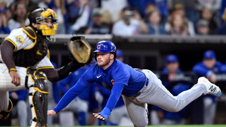 Chicago Cubs' Ian Happ (8) scores ahead of the throw...
