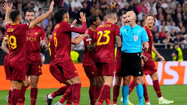 Roma players talk to Referee Anthony Taylor before he checks...