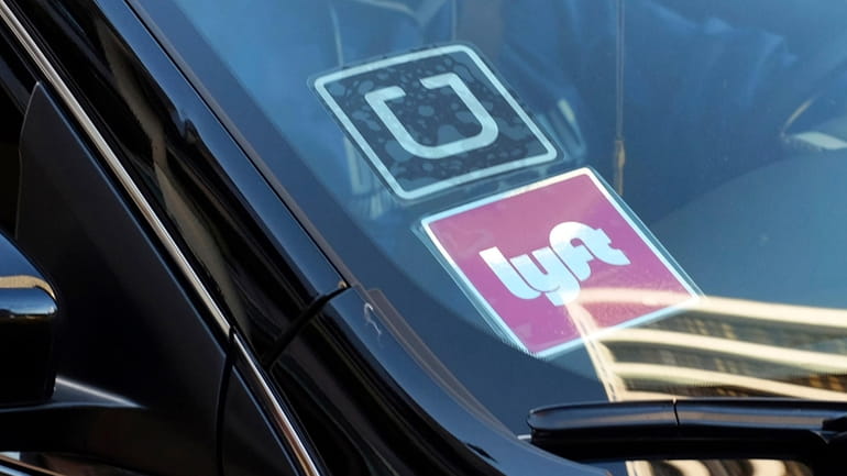 A ride share car displays Lyft and Uber stickers on...