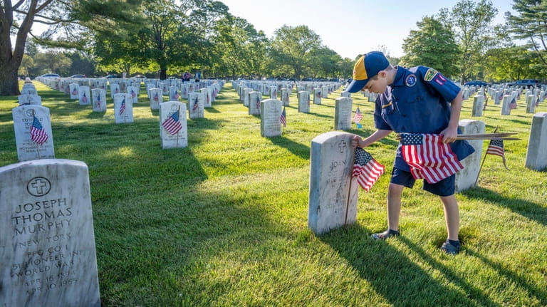 Anthony Wolk, 7, places flags at Long Island National Cemetery...