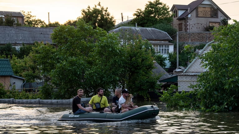 Volunteers evacuate a dog from a flooded neighborhood in Kherson,...