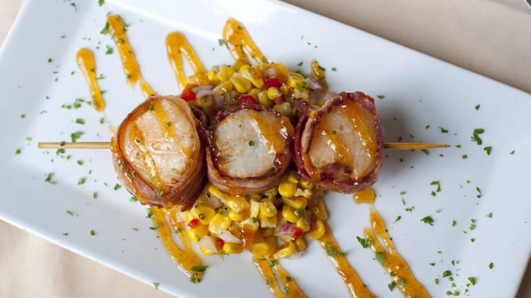 Bacon-wrapped sea scallops with a spicy apricot glaze is served...