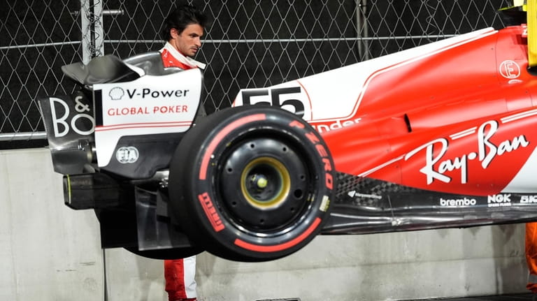 Ferrari driver Carlos Sainz, of Spain, looks at his car...