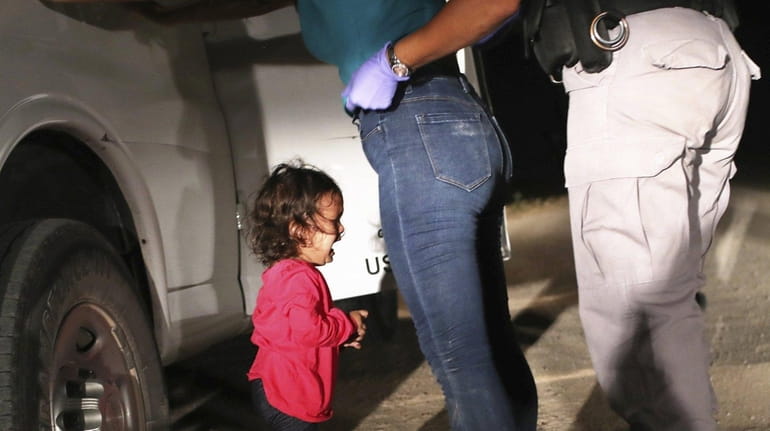 A 2-year-old Honduran asylum seeker cries as her mother is...