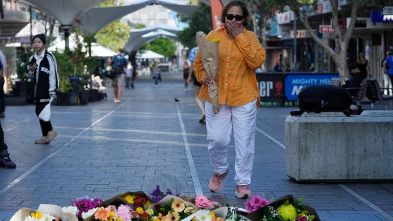A woman brings flowers to an impromptu memorial at Bondi...
