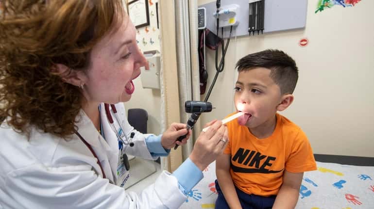 Jesus Bonilla, 6, is examined by pediatrician Gina F. Reinoso at...