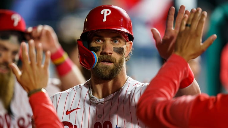 Philadelphia Phillies' Bryce Harper celebrates with teammates after his run...