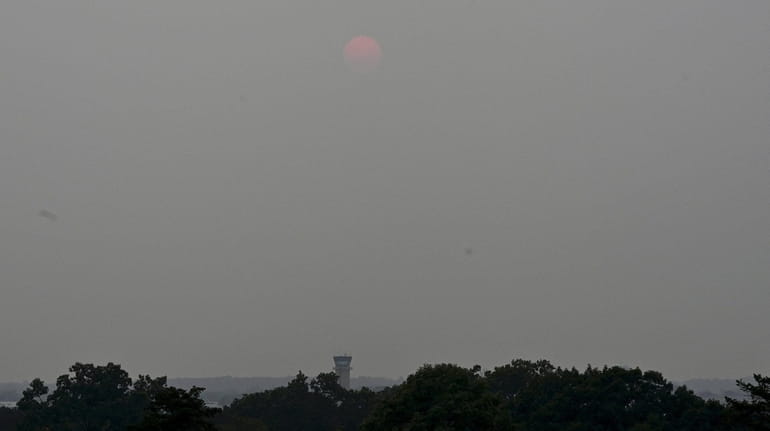 Barely visible through thick haze from Western wildfires, the sun...