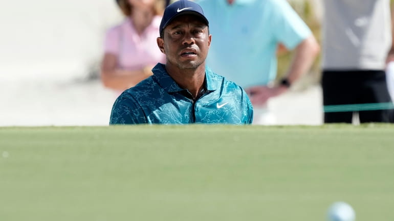 Tiger Woods watches his shot from a green side bunker...