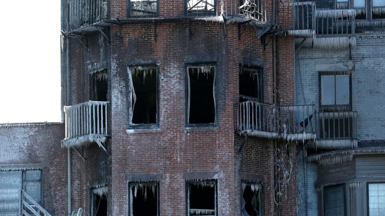 Ladders lean against the burned remains of a four-story brownstone,...
