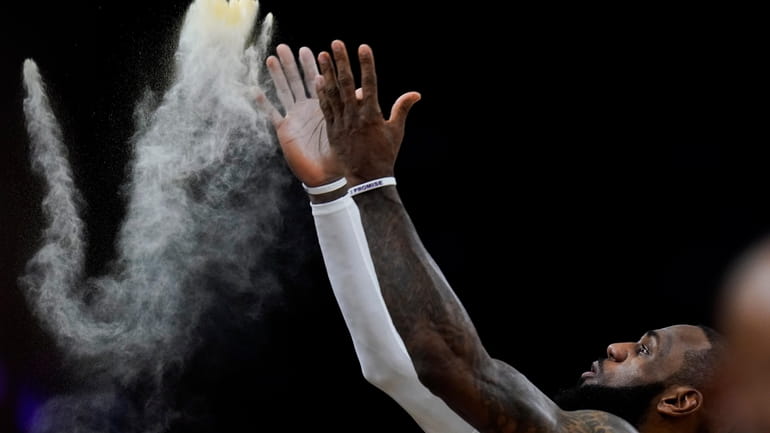 Los Angeles Lakers' LeBron James tosses powder before the team's...