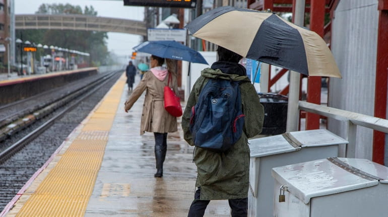 Commuters dodge raindrops at the LIRR station in Mineola on...