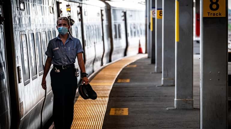 A Long Island Rail Road worker, with a mask, checks...