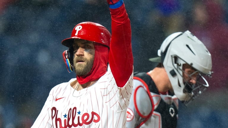 Philadelphia Phillies' Bryce Harper, left, reacts to his home run...