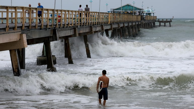 A surfer enters the water near Anglin's Fishing Pier as...