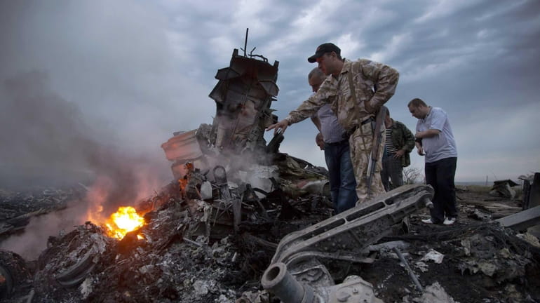 People inspect the crash site of a passenger plane near...