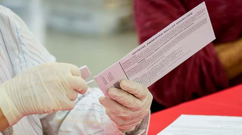 An NYC Board of Election staffer removes an absentee ballot...