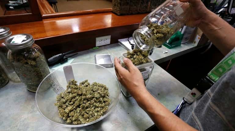 An employee places marijuana for sale into glass containers at...