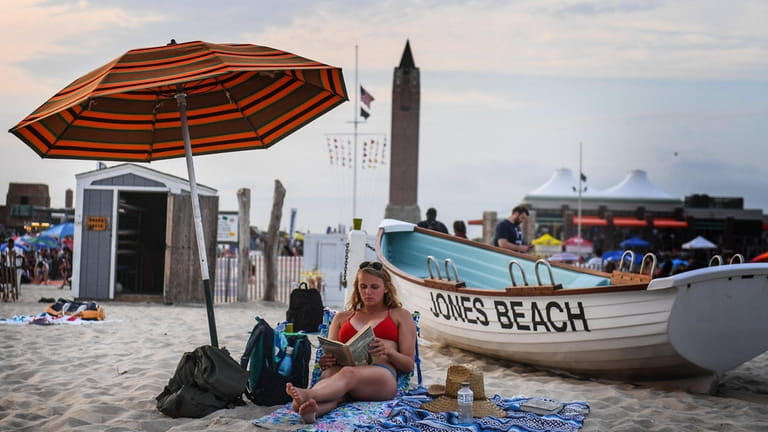 A woman reads a book in the sand at the...