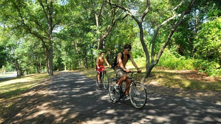 Bikers ride along a path at Bethpage State Park, which...