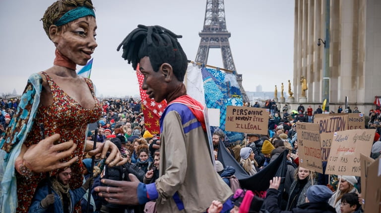 Opponents of France's immigration law carry models of migrants at...