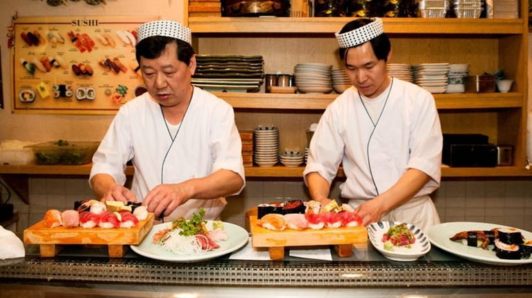 Akira Yamaguchi and his staff prepare sushi for diners at...