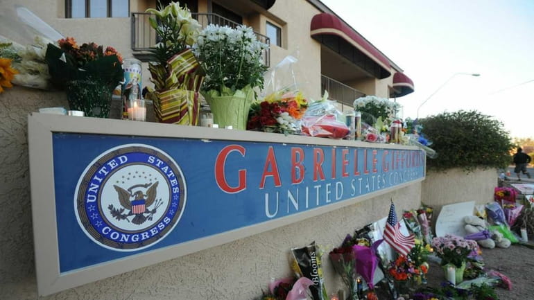 People leave flowers and candles outside the Tucson office of...